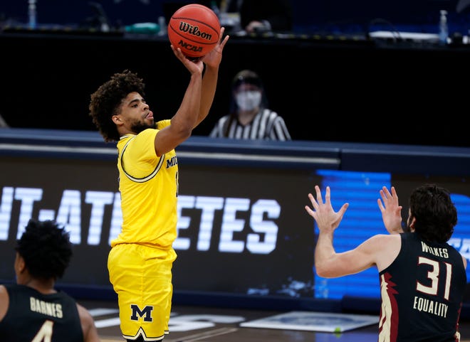 Michigan Wolverines guard Mike Smith (12) sinks a three-pointer over Florida State Seminoles guard Wyatt Wilkes (31) during the Sweet Sixteen round of the 2021 NCAA Tournament on Sunday, March 28, 2021, at Bankers Life Fieldhouse in Indianapolis, Ind.