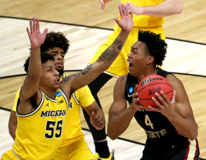 Florida State Seminoles guard Scottie Barnes (4) drives to the basket while being guarded by Michigan Wolverines guard Eli Brooks (55) during the Sweet Sixteen round of the 2021 NCAA Tournament on Sunday, March 28, 2021, at Bankers Life Fieldhouse in Indianapolis, Ind.
