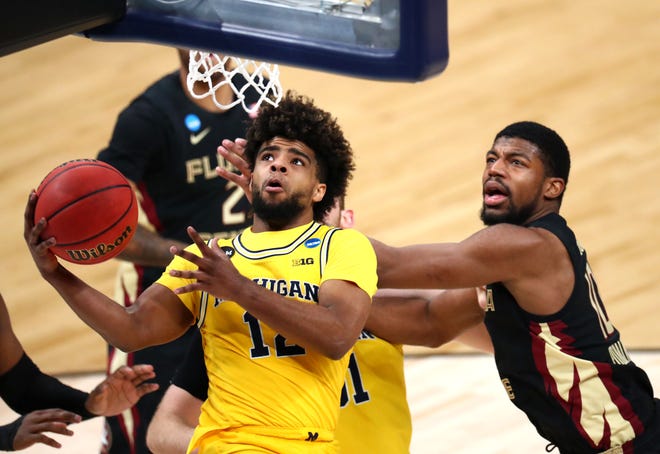 Michigan Wolverines guard Mike Smith (12) drives past a slew on Florida State defenders for a basket during the Sweet Sixteen round of the 2021 NCAA Tournament on Sunday, March 28, 2021, at Bankers Life Fieldhouse in Indianapolis, Ind.