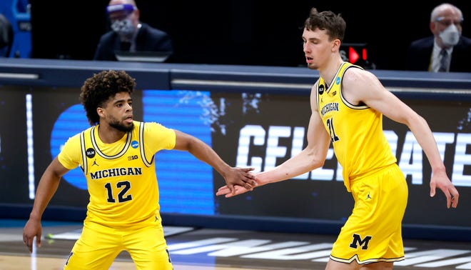 Michigan Wolverines guard Mike Smith (12) high fives Michigan Wolverines guard Franz Wagner (21) after hitting a three-pointer against Florida State during the Sweet Sixteen round of the 2021 NCAA Tournament on Sunday, March 28, 2021, at Bankers Life Fieldhouse in Indianapolis, Ind.